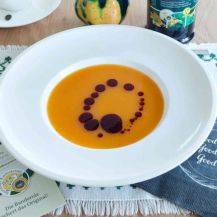 Steirisches Kürbiskernöl dekorativ auf Suppe angerichtet – feine Tropfen für intensiven Geschmack, dunkelgrün