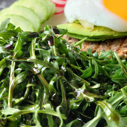 Steirisches Kürbiskernöl auf frischem Rucola-Salat mit Avocado und Ei